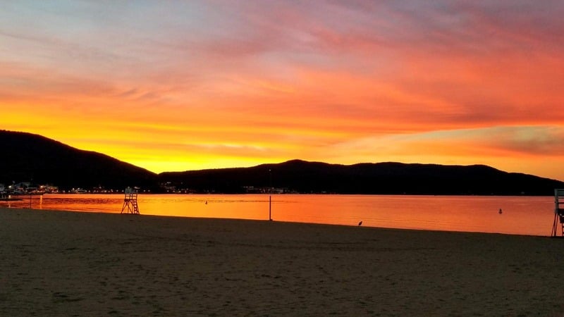 a beach at sunset with mountains in the background